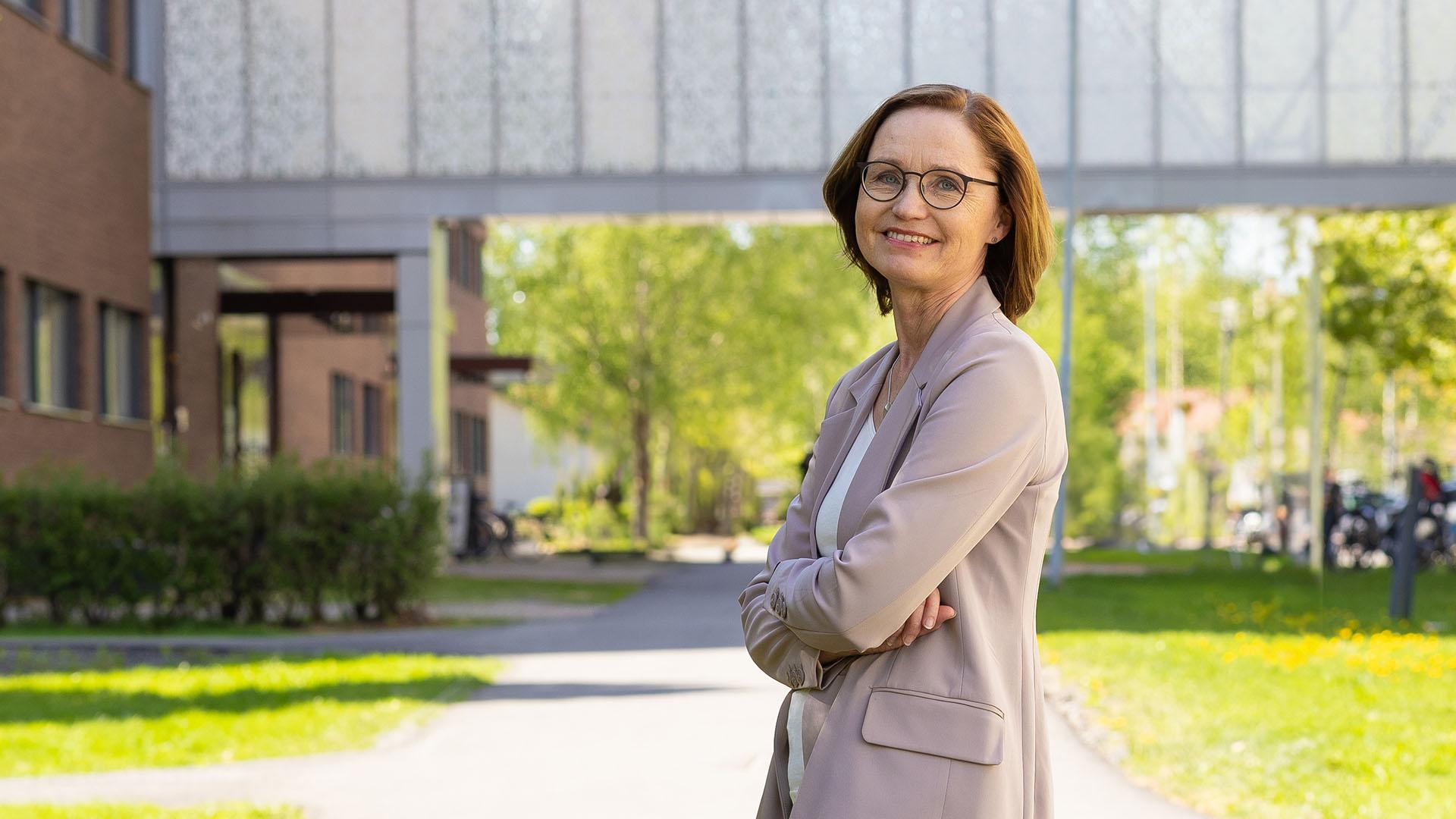 Kuvassa nainen poseeraa kameralle kesäisessä maisemassa